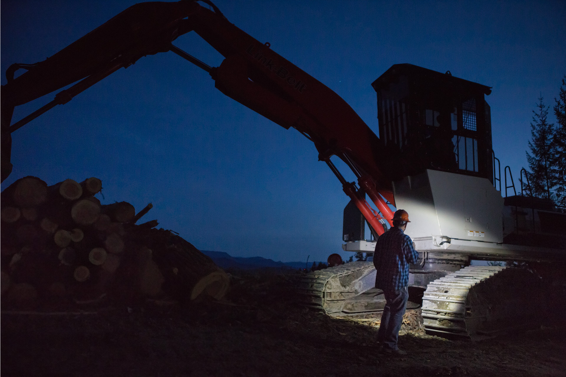 Brand Photography for Coast Products showing person shining flashlight on heavy machinery at night