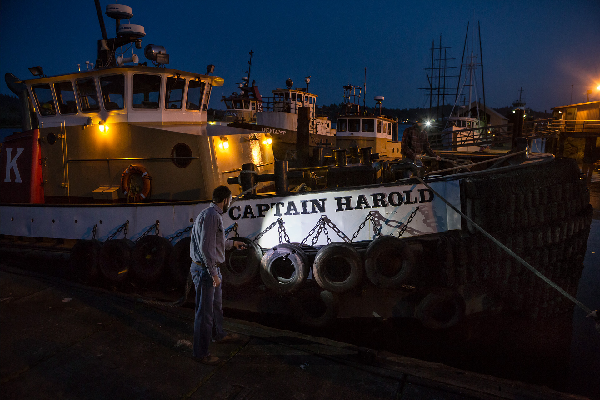 Brand Photography for Coast Products show boat captain shining flashlight beam on tug boat