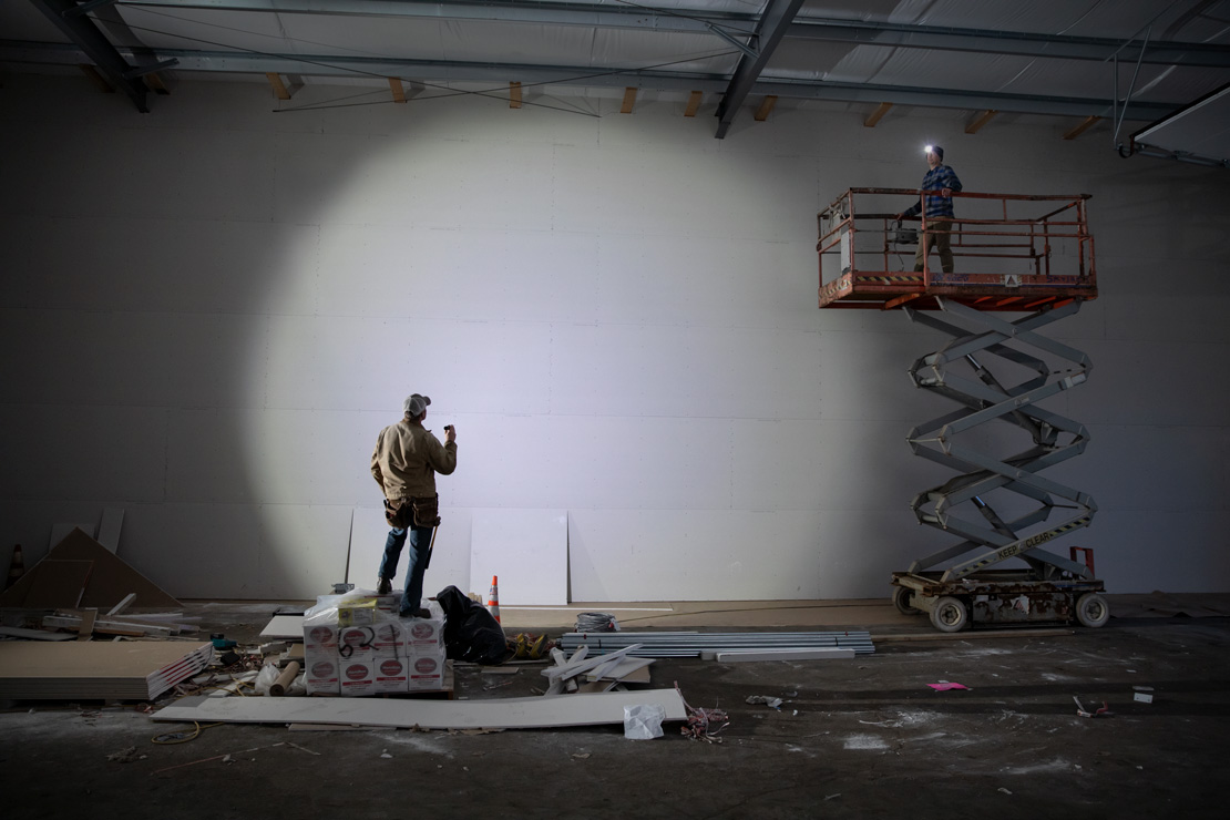 Man shining wide beam on warehouse wall with a Coast flashlight