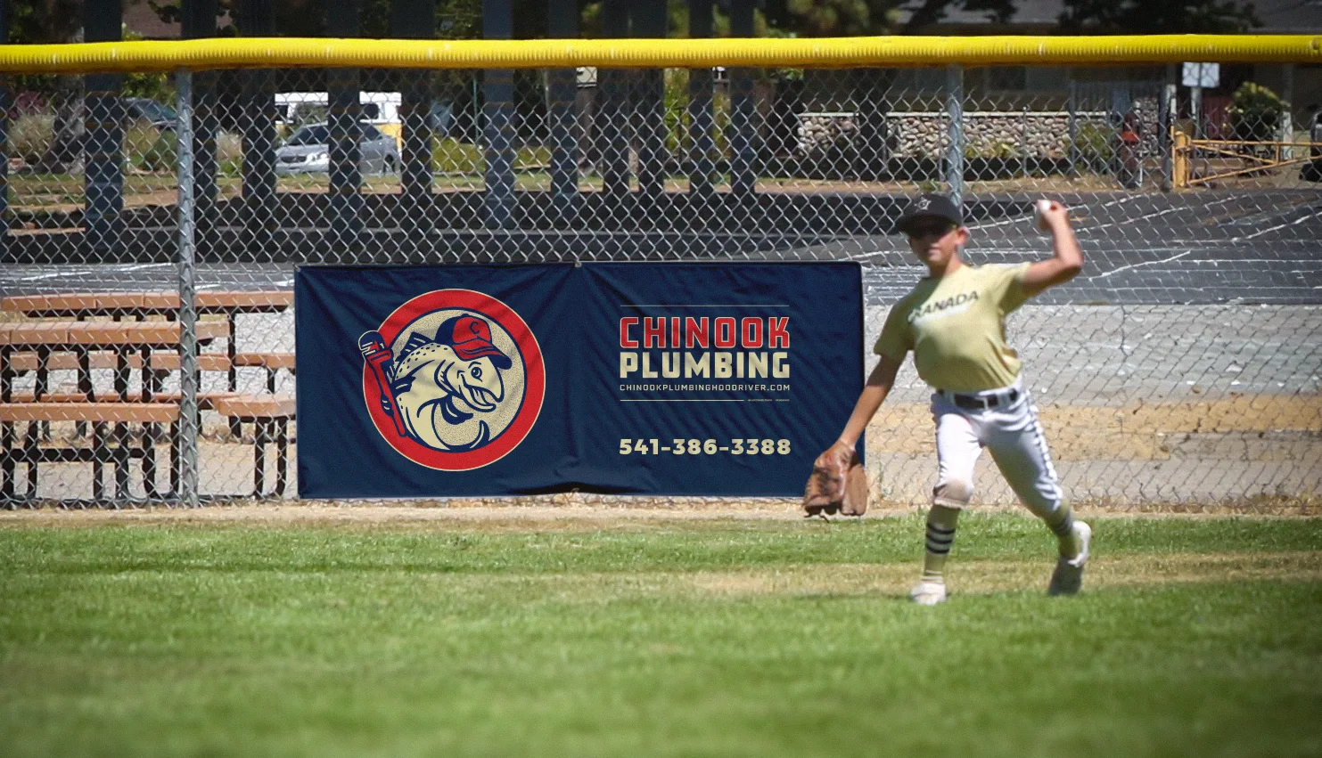 Chinook Plumbing sponsor banner depicting the new branding hanging on outfield fence